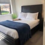 single bed shown in Denver Detox Center patient room with view of grass and trees out the window