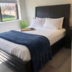 single bed shown in Denver Detox Center patient room with view of grass and trees out the window