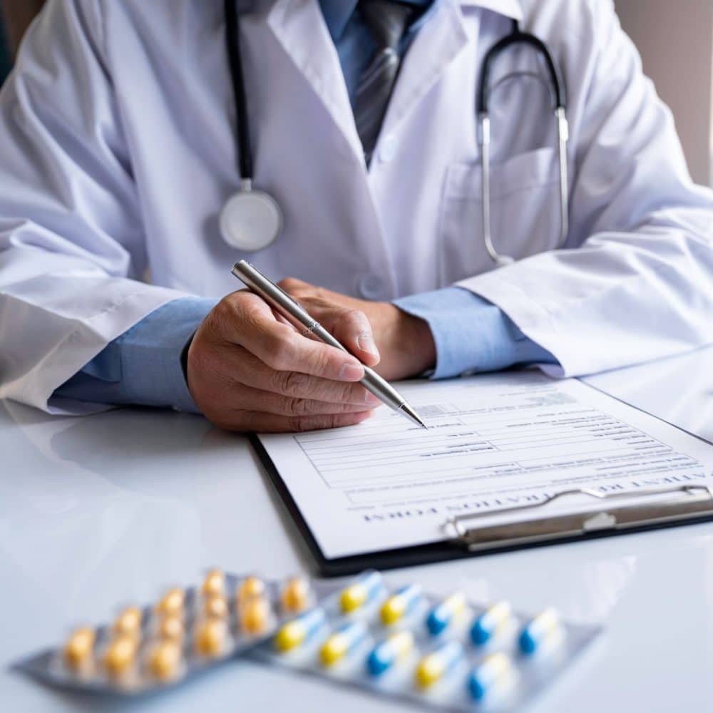 male medicine doctor hand holds the bottle of pills and writes a prescription to the patient at the worktable. Panacea and life save, prescribing treatment legal drug store concept.