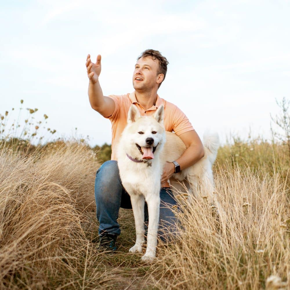 Happy man playing with dog on the field